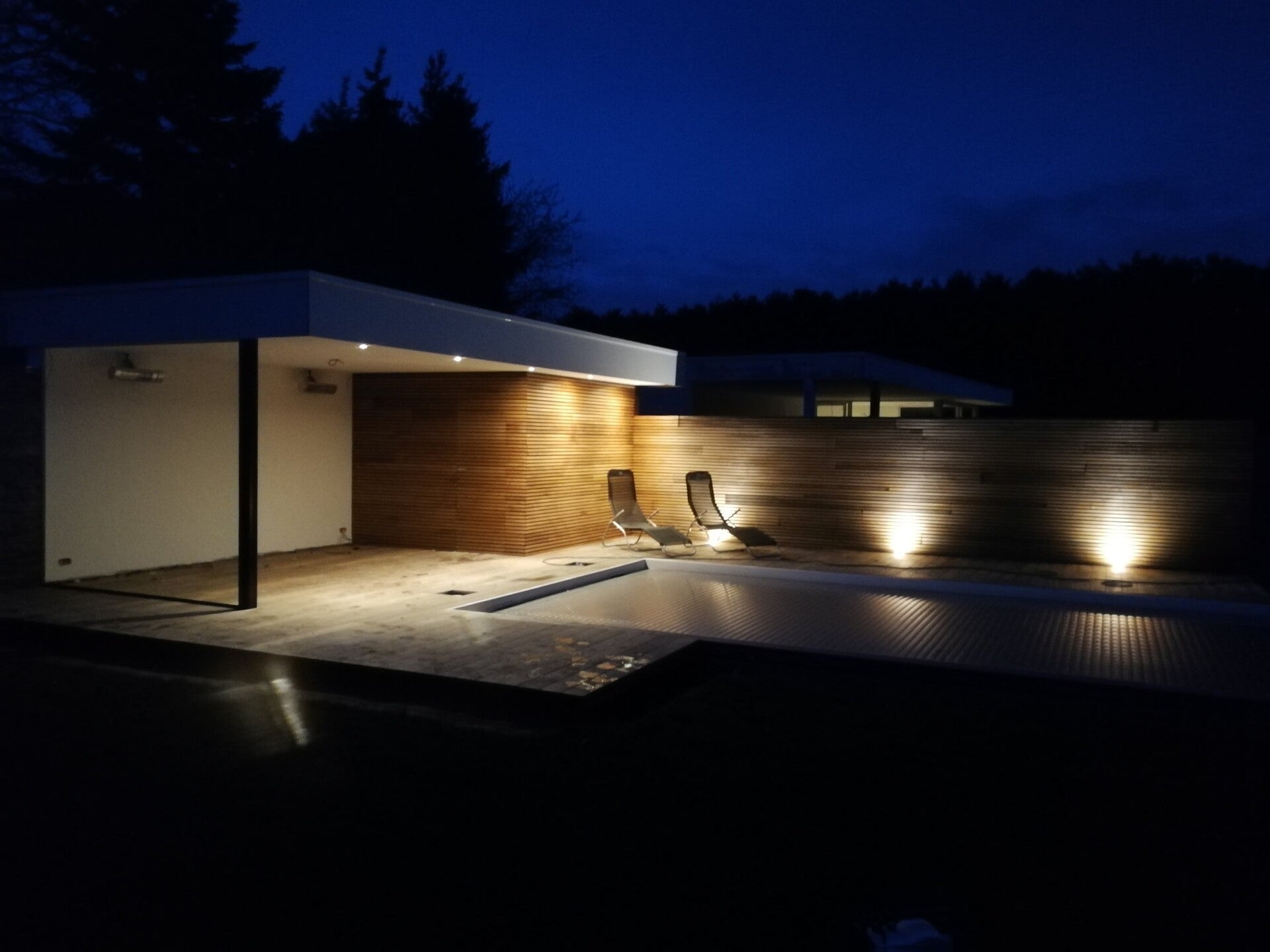 Verlicht poolhouse en zwembadterras bij avond