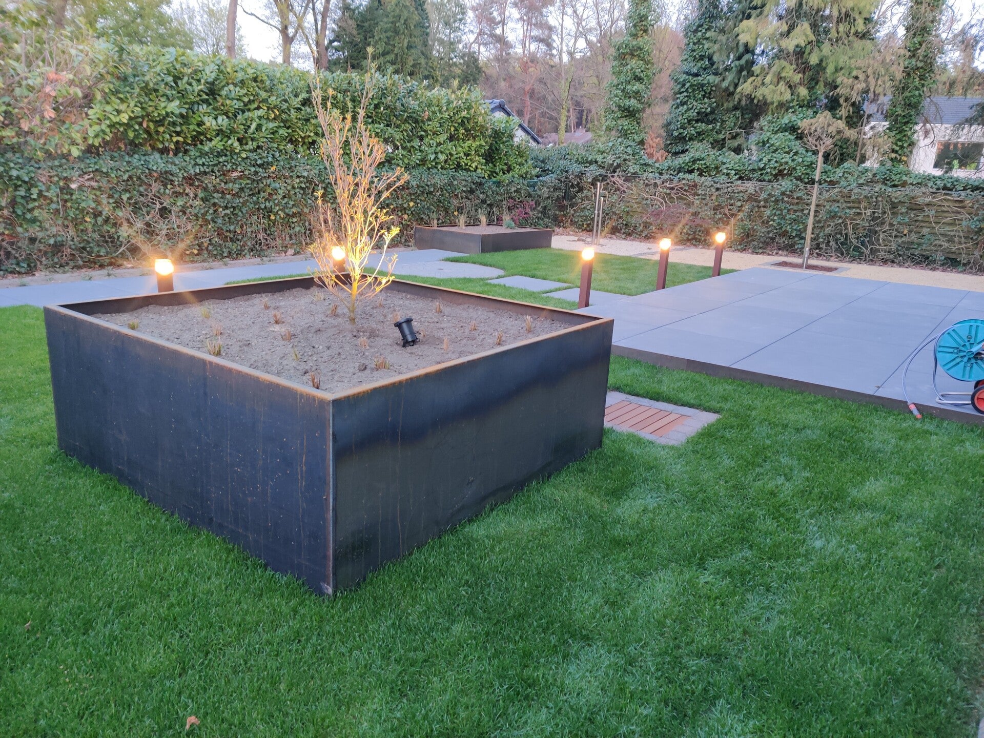 Cortenstalen plantenbak met verlichting in een nieuw aangelegde tuin