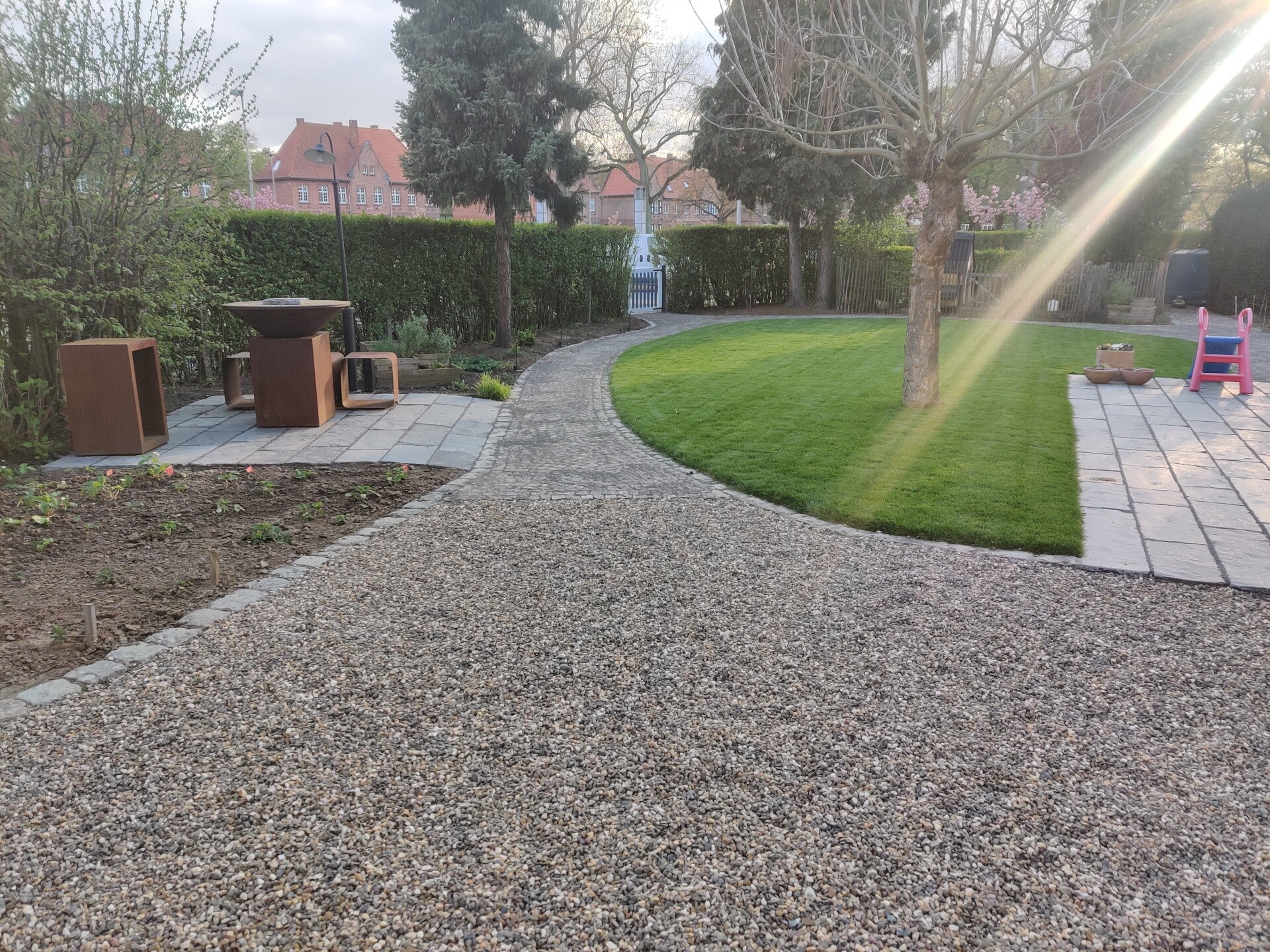 Grindpad met kasseiboord, rond gazon en terras met vuurschaal